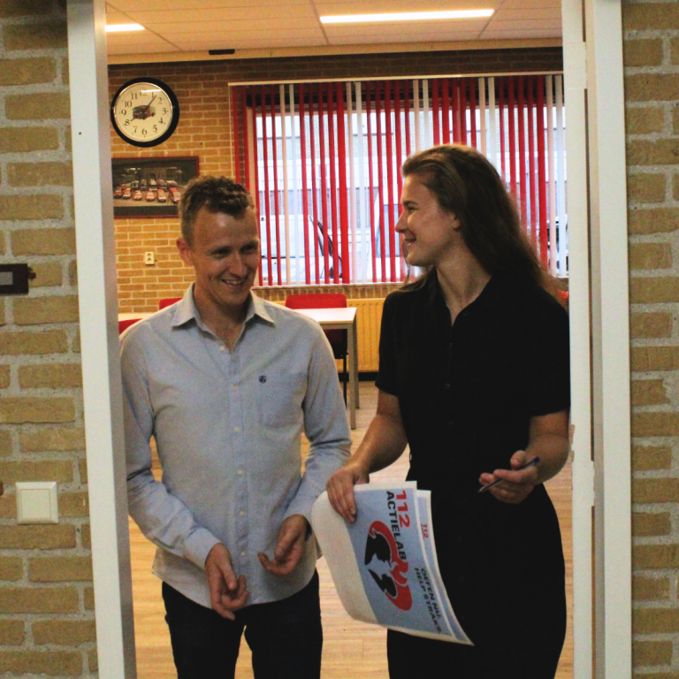 MBO Twee mensen lopen door een deur, een vrouw houdt een document vast en lacht naar een man.